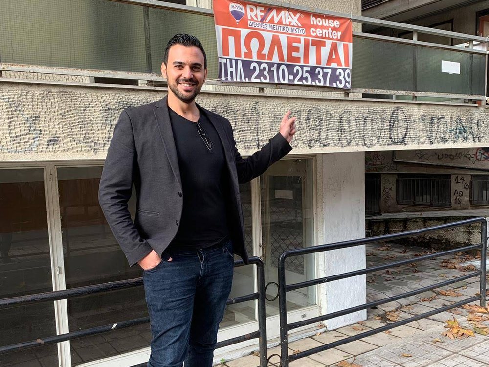 יקיר עומד מול הבניין בקריזוטו 15, מתחת לשלט המכירה של המוכר